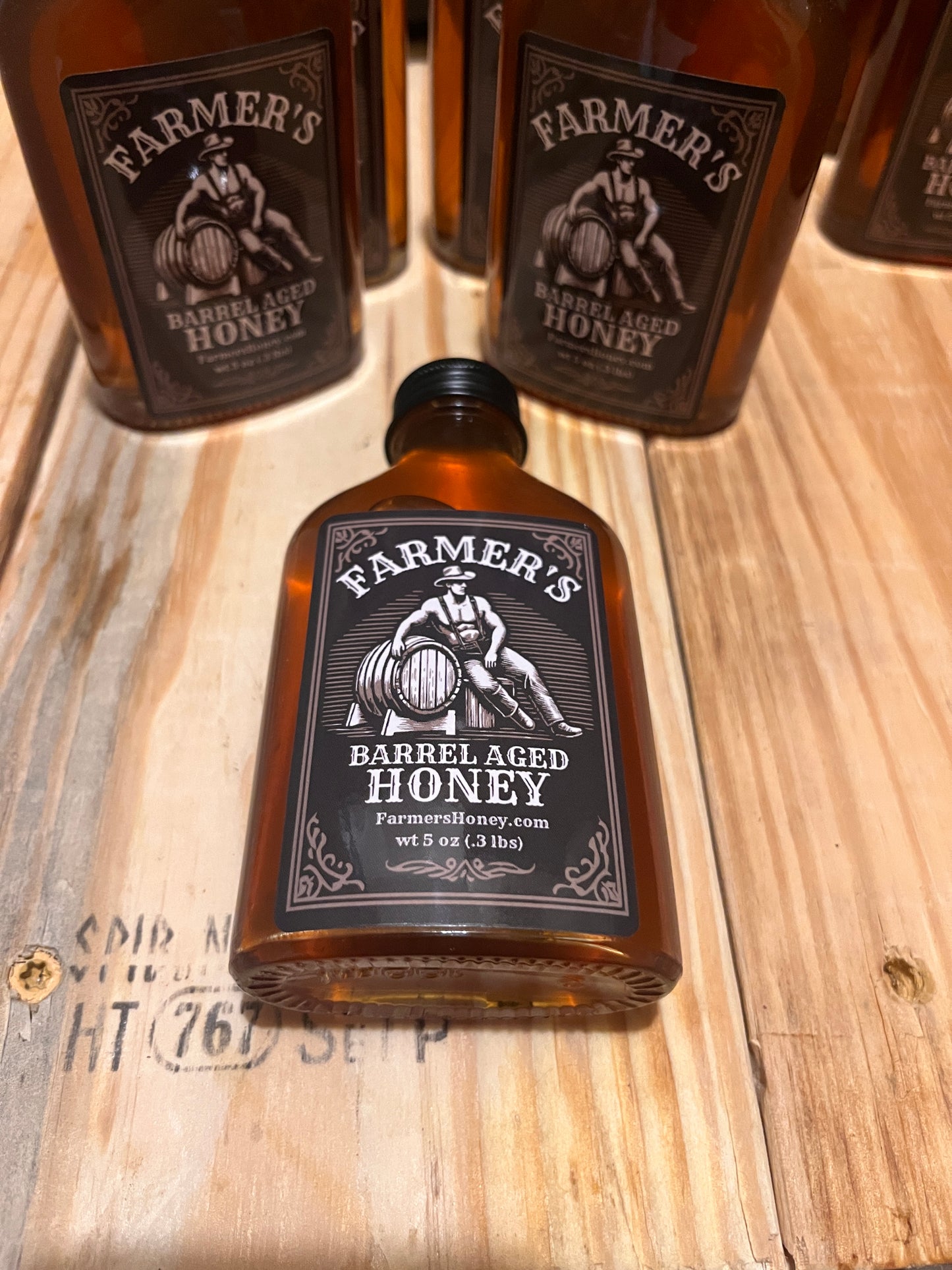 multiple bottles of farmer's barrel aged honey on a table